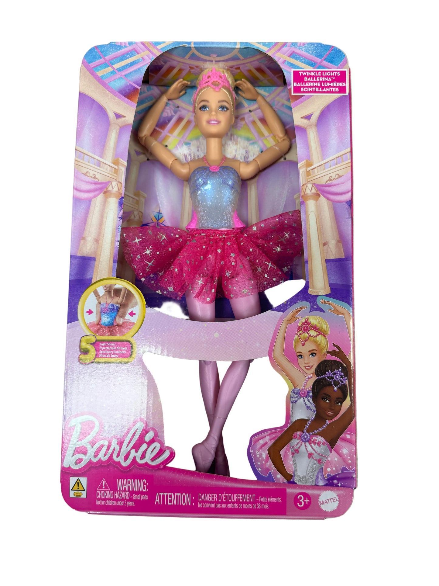 Barbie doll in a pink and blue dress with a star on its head in packaging on a wooden surface.