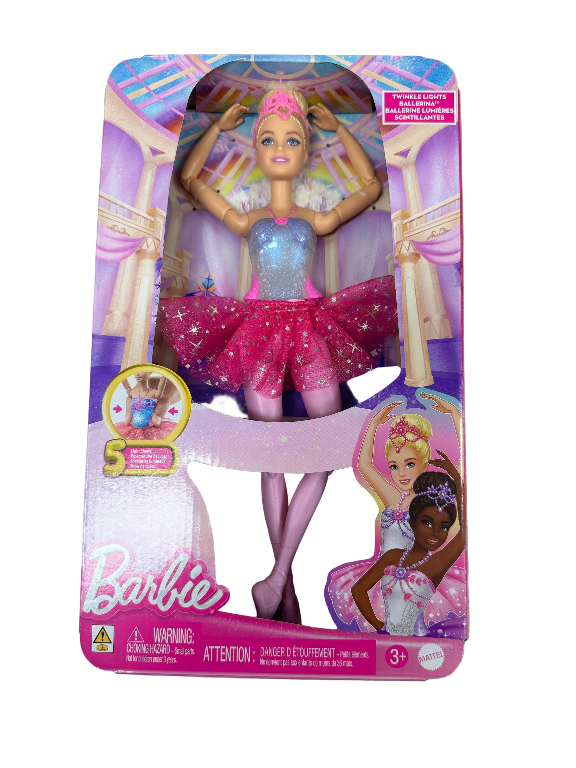 Barbie doll in a pink and blue dress with a star on its head in packaging on a wooden surface.