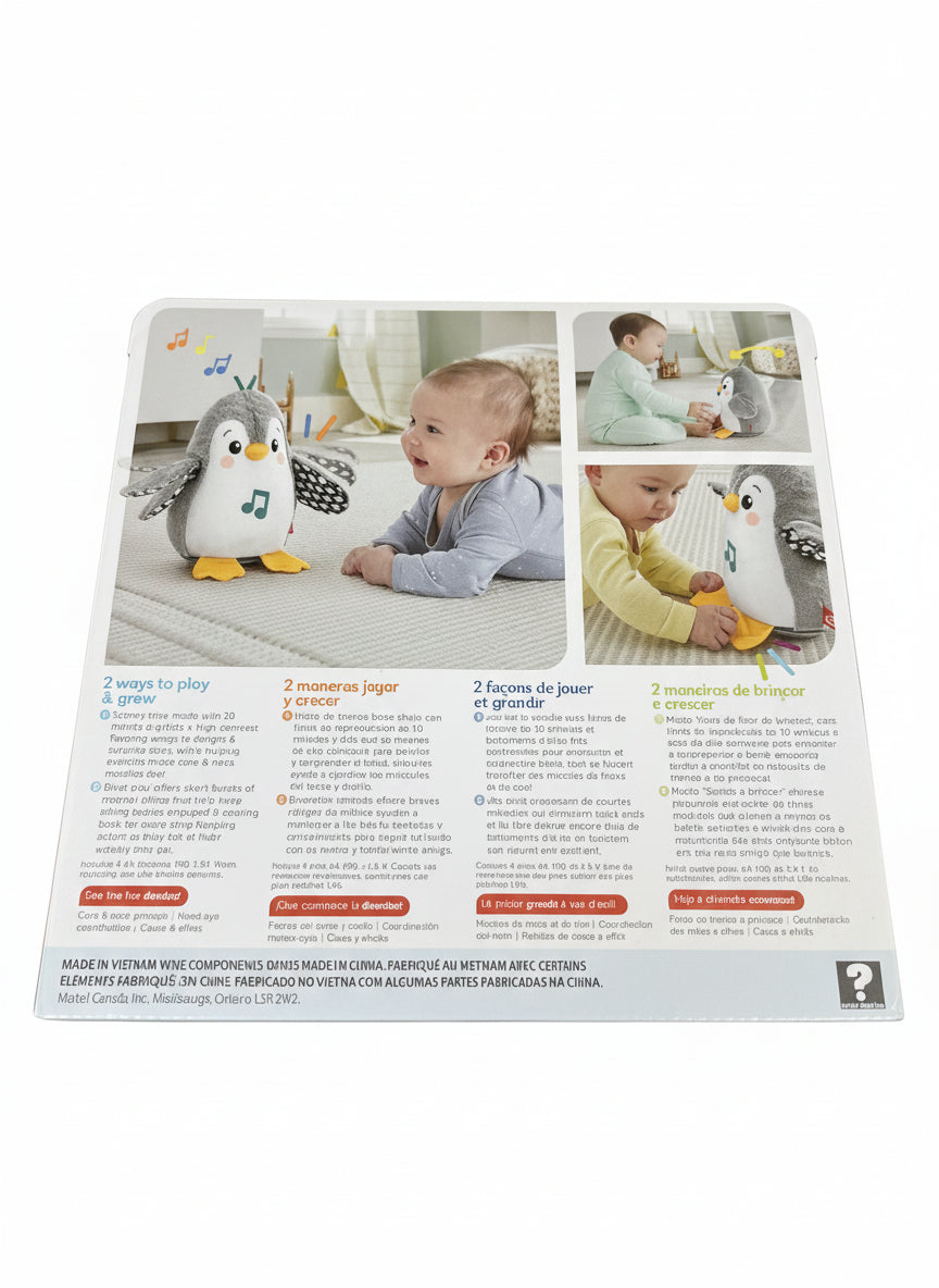 Product packaging with images of a baby and penguin toy, on a light wooden surface.