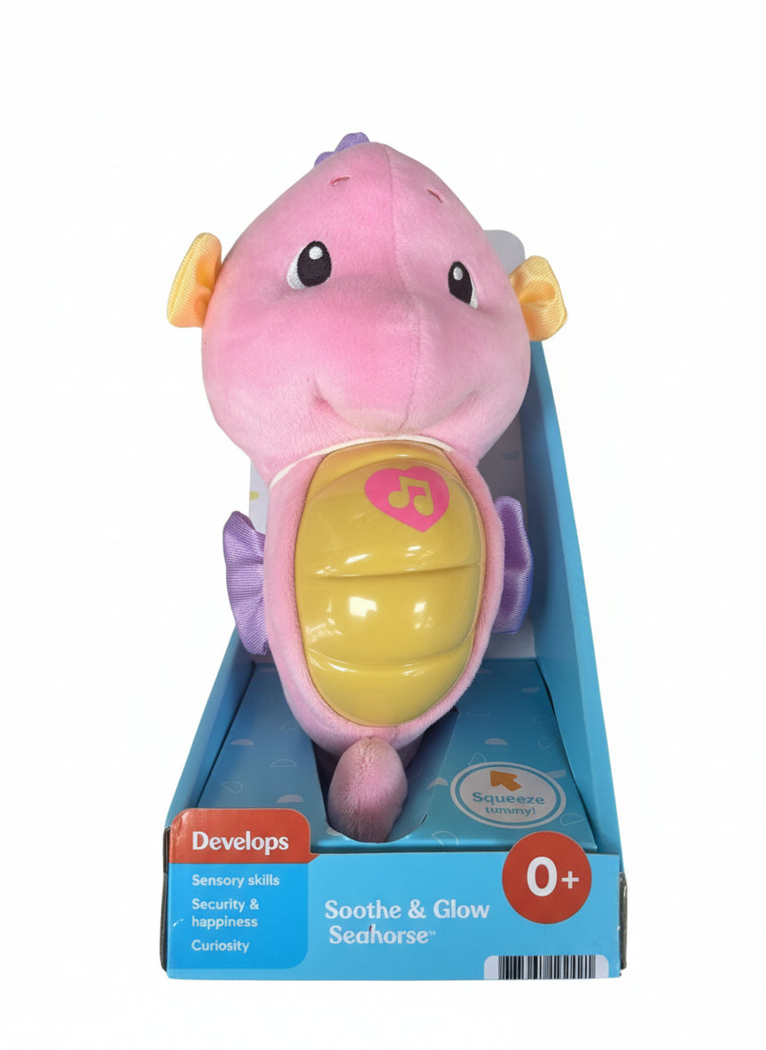 Pink and yellow plush seahorse toy in packaging on a gray surface
