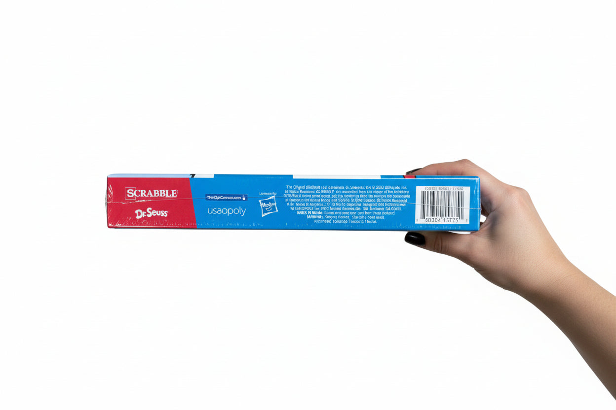 Scrabble game box held by a hand on a wooden floor
