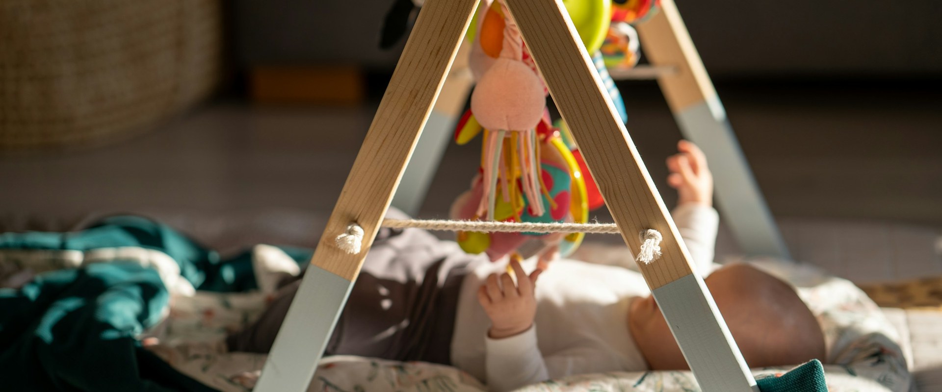 Baby on activity mat with wooden play gym — Hero banner Fisher-Price